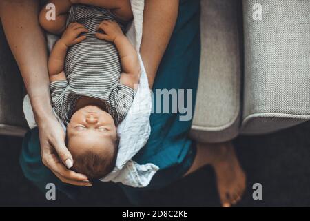 Vue du dessus photo d'une mère caucasienne tenant son nouveau-né fille sur ses jambes dormant en posant sur un canapé près de l'espace libre Banque D'Images