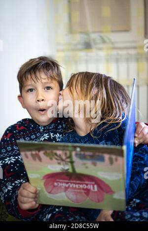 Deux frères et sœurs en pyjama avec livre, soeur baiser frère, drôle émotions énorme maison Banque D'Images