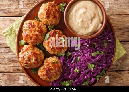 Boulettes de viande frites au chou rouge chaud et sauce en gros plan dans une assiette sur la table. Vue horizontale du dessus Banque D'Images