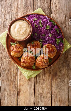 De délicieux boulettes de viande servies avec une garniture de chou rouge et une sauce en gros plan dans une assiette sur la table. Vue verticale du dessus Banque D'Images