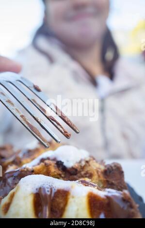 Petite fille mangeant des gaufres couvertes de garniture au chocolat noir et de céréales en poudre. Concept de dessert sucré à haute teneur en calories pour les enfants Banque D'Images