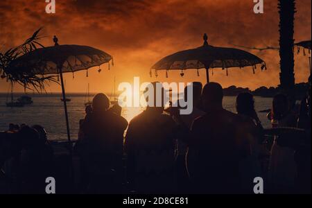 Groupe de pf personnes qui traînaient dans un café public ou une discothèque pendant le coucher de soleil orange vif sur le Calo des Moro à Ibiza. Îles Baléares. Europe, SPAI Banque D'Images