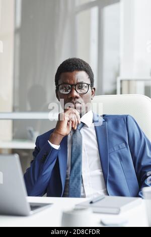 Portrait d'un leader africain de la confiance dans les lunettes de vue appareil photo assis sur son lieu de travail Banque D'Images