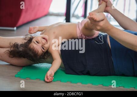 Le père caucasien fait du sport, de la forme physique et du yoga avec sa petite fille de mère latine dans la salle à manger de la maison, ils ont du plaisir pendant qu'ils font l'exe Banque D'Images