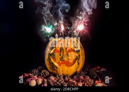 Citrouilles sculptées pour Halloween, la tête de Jack est sur la table. Feux d'artifice dans une citrouille. Arrière-plan sombre. Banque D'Images