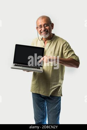 Homme adulte ou grand-père asiatique indien présentant un ordinateur portable vierge écran sur fond blanc Banque D'Images