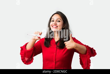 Jeune femme asiatique indienne vérifiant la température avec un thermomètre ou de l'oxygène niveau à l'aide d'un oxymètre ou de médicaments Banque D'Images