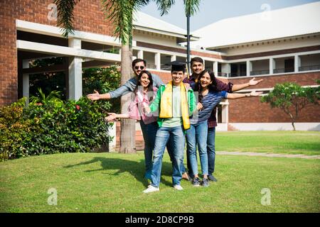 Les étudiants indiens asiatiques reçoivent un certificat tandis que leurs amis célèbrent en plein air sur le campus universitaire Banque D'Images