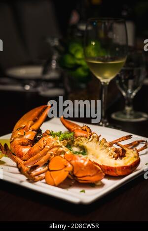 un homard entier grillé coupé en deux et servi avec quartiers de citron Banque D'Images