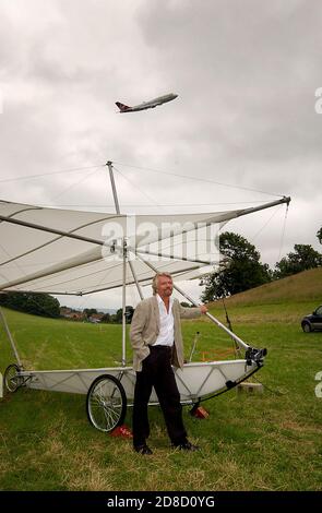 Richard Branson à côté d'une réplique du planeur de Sir George Cayley, avec un Boeing 747 de Virgin Atlantic (G-VAST) faisant un bas vol aérien, avant lui r Banque D'Images