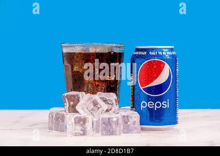 Londres, Royaume-Uni - octobre 29 2020: Glace froide canette de Pepsi à côté d'un verre plein de soda avec des cubes de glace et de condensation sur un fond bleu. Banque D'Images