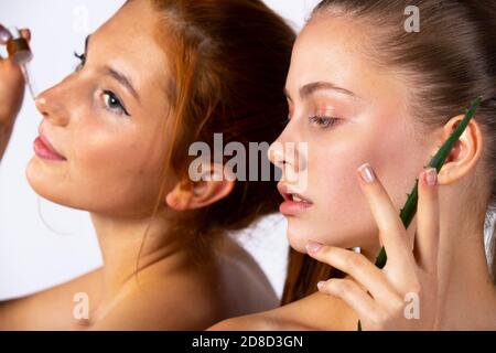 Jeunes filles et posant devant l'appareil photo. Photo agrandie. Fille avec des feuilles d'aloès et une pipette avec du sérum. Beauté, spa et concept de santé Banque D'Images