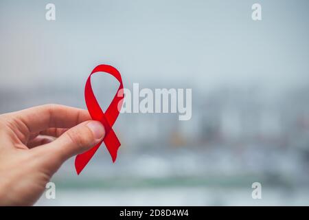 Ruban rouge symbole VIH, sensibilisation au cancer du sida avec ombres, tir en studio isolé sur fond rouge, concept de médecine de santé, Journée mondiale du sida Banque D'Images