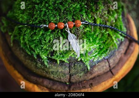 Suspension en métal à plumes avec bracelet rudraksha à perles de graines sur mousse polypore Banque D'Images