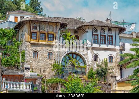 Gjirokaster ville/ Albanie – 2 août 2020 : architecture traditionnelle – ancienne maison avec toit en pierre grise et fenêtres voûtées. Paysage urbain d'été historique Banque D'Images