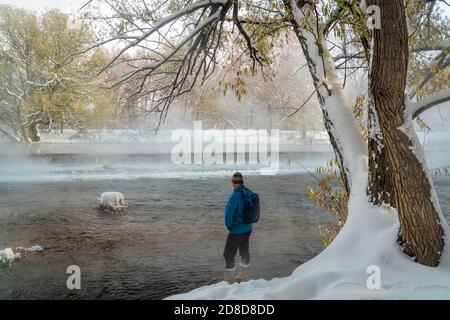 Un homme âgé fait de la randonnée le long de la rivière poudre à fort Collins, Colorado - paysage d'automne brumeux avec une neige fraîche Banque D'Images