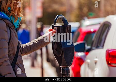 Une femme paie le parking sur le poteau du compteur du parc de la rue dans le Ville des États-Unis Banque D'Images