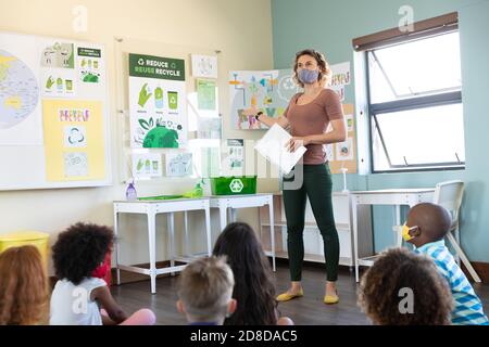 Une enseignante portant un masque facial enseignant aux élèves en classe à école Banque D'Images