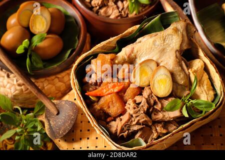 Gudeg Jogja. Le plat javanais se compose de ragoût de fruits de Jack, de curry de poulet et de ragoût épicé de craquelins en peau de bétail dans un panier de bambou Banque D'Images