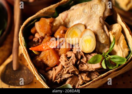 Gudeg Jogja. Le plat javanais se compose de ragoût de fruits de Jack, de curry de poulet et de ragoût épicé de craquelins en peau de bétail dans un panier de bambou Banque D'Images