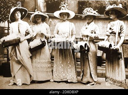 1912 . Une vieille photographie de cinq femmes qui vendent des roses à des fins de charité lors de la toute première Journée des roses Alexandra ------ L'Alexandra Rose Day (en juin) est un événement caritatif de collecte de fonds organisé au Royaume-Uni depuis 1912 par Alexandra Rose Charities. Il a été lancé pour la première fois à l'occasion du 50e anniversaire de l'arrivée de la reine Alexandra de son Danemark natal au Royaume-Uni. La Reine a demandé que l'anniversaire soit marqué par la vente de roses sauvages artificielles à Londres, faites par de jeunes femmes et filles handicapées du John Groom Industrial Training Home, pour recueillir des fonds pour ses œuvres caritatives préférées. Banque D'Images