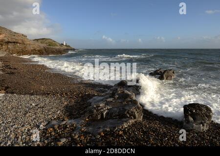 Les vagues se brisent au-dessus du rivage à la baie de Bracelet sur le Les mumbles ont été bassé dans des couleurs claires du soir Banque D'Images