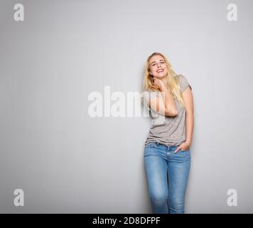 Portrait d'une jeune femme blonde confiante souriant sur fond gris Banque D'Images