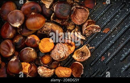 Châtaignes grillées sur fond de béton noir. Châtaignes pour Noël en gros plan. Papier peint alimentaire Banque D'Images
