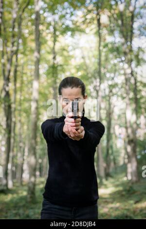Femme avec une arme de poing orientée vers la caméra. Banque D'Images