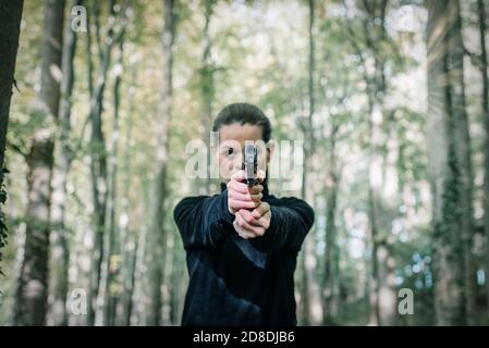 Femme avec une arme de poing orientée vers la caméra. Banque D'Images