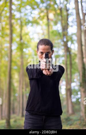 Femme tenace qui cherche un pistolet dans les bois. Banque D'Images