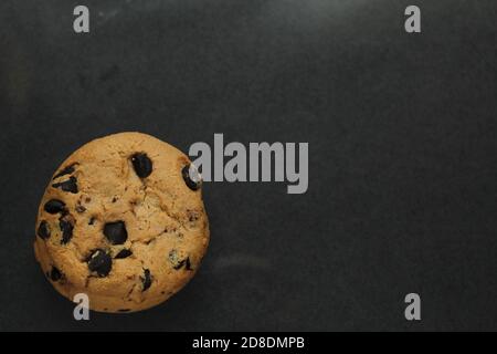 biscuits de fond de nourriture autour avec des gouttes de chocolat couché sur un arrière-plan noir foncé vue du dessus de l'espace de copie Banque D'Images