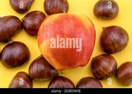 châtaignes et pomme de gala royale rouge isolée sur fond jaune dans la vue de dessus Banque D'Images