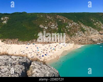 Baigneurs de soleil sur la plage de Porthcurno, en Cornouailles, avec mer turquoise, pris de falaise près du théâtre de Minack Banque D'Images