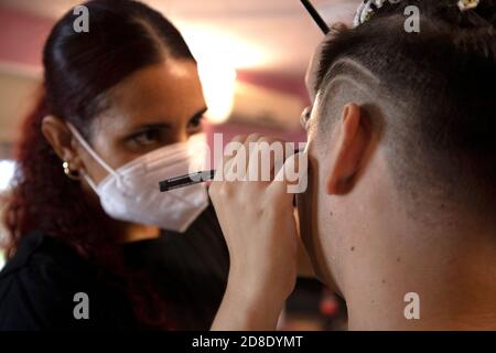 Maquilleuse avec un masque pour peindre le visage d'un homme halloween Banque D'Images
