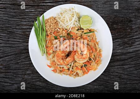 Photo en hauteur d'un plat thaïlandais traditionnel de crevettes avec nouilles de riz sautées, tiré d'en haut sur une texture rustique Banque D'Images