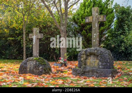 Deux pierres à tête entourées de feuilles d'automne dans le chantier naval de St Mary, Burton Latimer, Northamptonshire, Royaume-Uni Banque D'Images