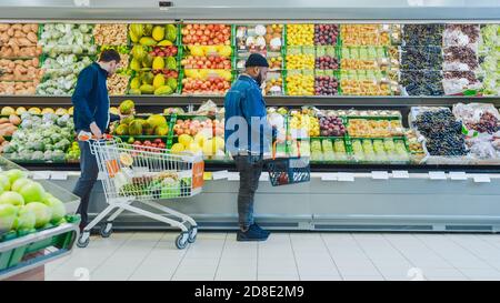 Au supermarché: Happy Black stylisé Guy avec panier Shopping pour les fruits et légumes biologiques dans la section des produits frais du magasin. Banque D'Images