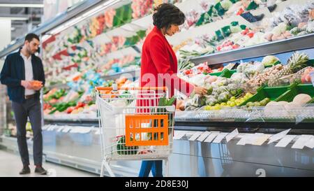Au supermarché: Belle jeune femme marche à travers la section des produits frais, choisit des fruits et des légumes. Client Shopping pour des fruits et Banque D'Images