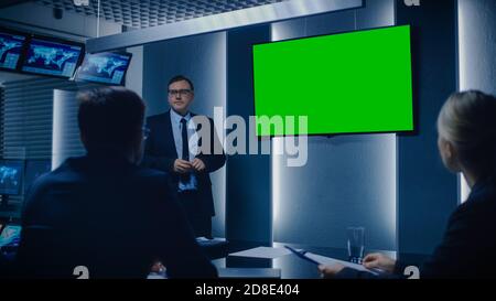 Chef de la stratégie présentant un rapport à un conseil d'administration et à des partenaires d'affaires, à l'aide de l'écran de maquette verte dans la salle de surveillance. Banque D'Images