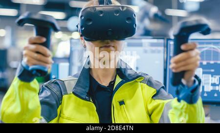 Portrait Femme Ingénieur en mécanique portant un casque de réalité virtuelle et utilisant des contrôleurs, elle utilise la technologie VR pour la conception industrielle, le développement Banque D'Images