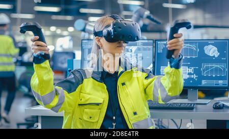 Portrait Femme Ingénieur en mécanique portant un casque de réalité virtuelle et faisant des gestes avec des contrôleurs, elle utilise la technologie VR pour la conception industrielle Banque D'Images