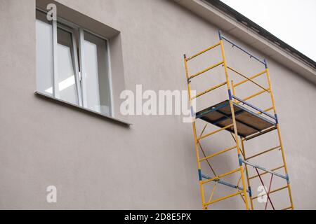 Réparation extérieure et rénovation d'une maison d'appartement à l'aide de peinture bleue métal petit échafaudage tour. Coin d'un immeuble urbain typique Banque D'Images