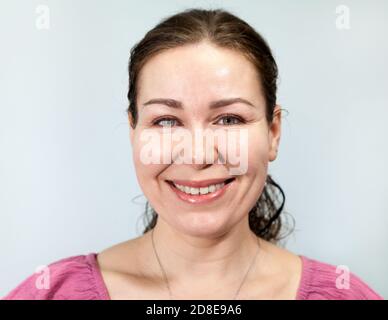 Femme adulte très souriante, portrait sur fond gris, série d'émotions. Banque D'Images