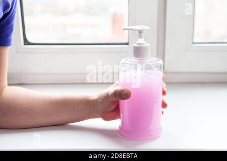 Flacon de désinfectant pour les mains caucasien femelle avec gel antibactérien rose Banque D'Images