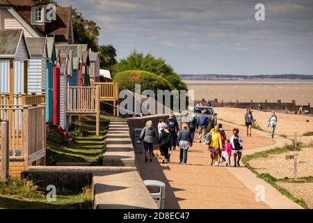 Royaume-Uni, Kent, Whitstable, Tankerton Beach, marcheurs sur la promenade en dessous des cabanes de plage Banque D'Images