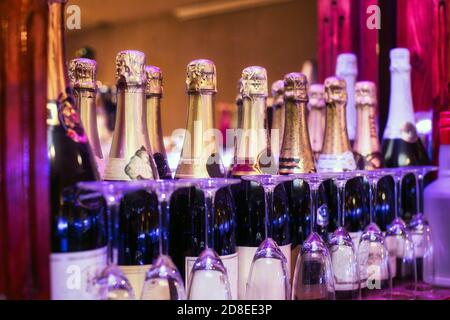 Bouteilles de champagne colorées dans une rangée au bar avec des verres, concept de fête dans différentes couleurs Banque D'Images