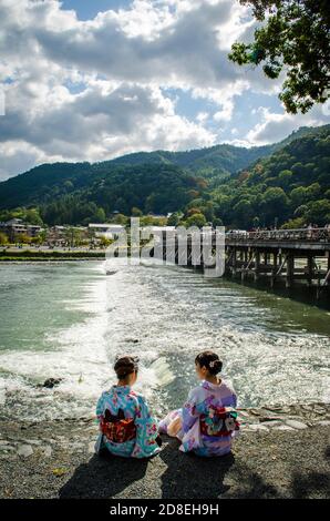 Deux femmes de kimono sont assises près de la rivière Kamo à Arashiyama à Kyoto, au Japon. Banque D'Images