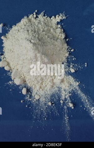 la farine ou le sucre en poudre est entassé dans un tas sur un arrière-plan bleu clair, une vue de dessus est présente copier l'espace pour le texte Banque D'Images