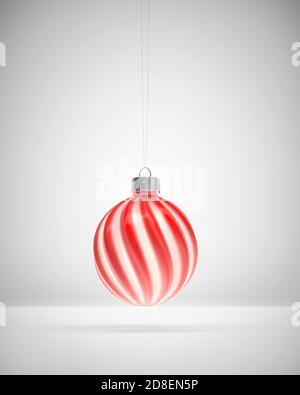 Boule de Noël à rayures tordues rouges et blanches suspendues. Arrière-plan ombré blanc. Décoration de Noël, concept d'atmosphère festive. Banque D'Images